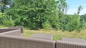 Wicker furniture outdoors with a dense green forest in the background. - WesterOurthe 6 persons with sauna (Durbuy)