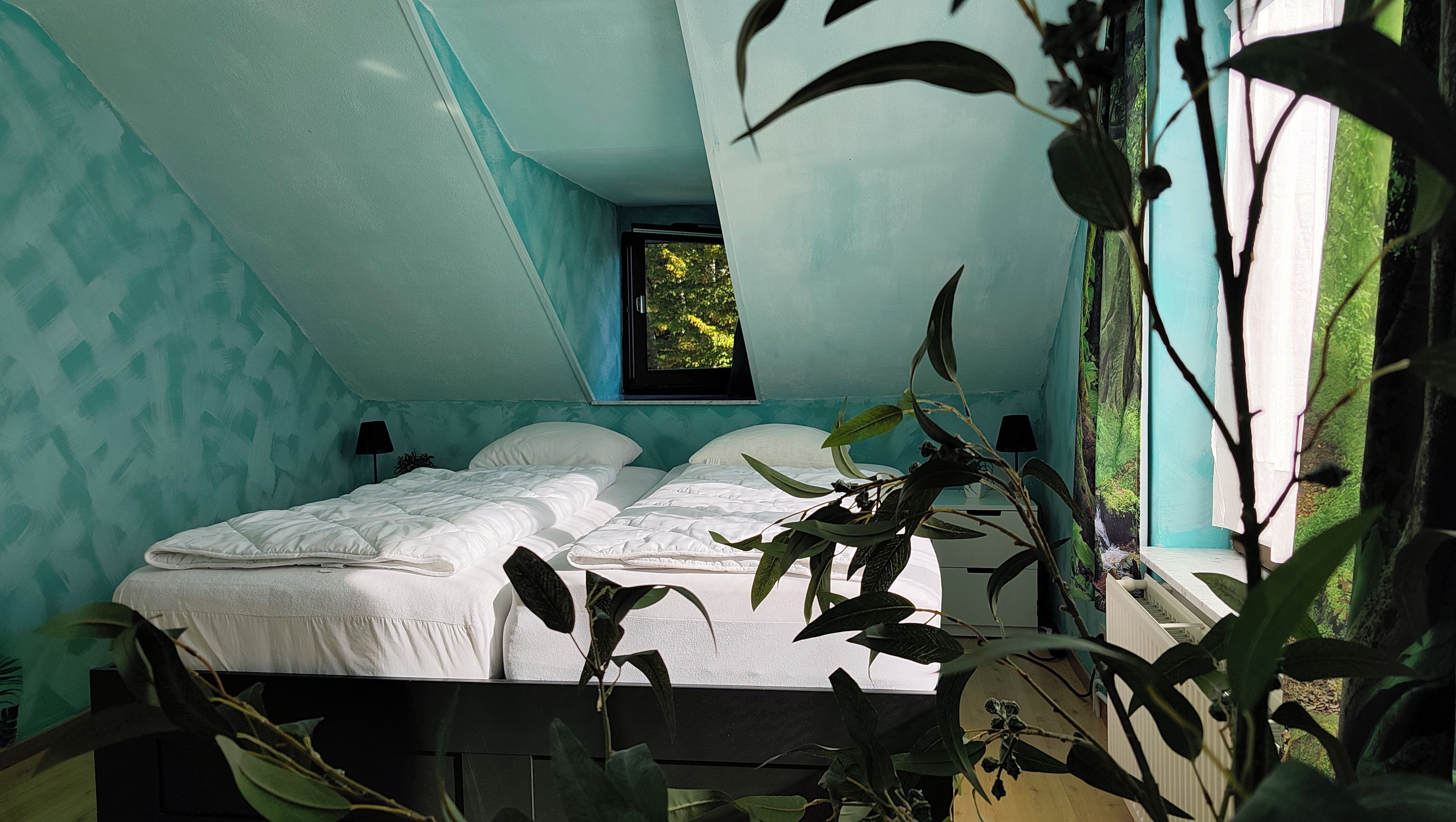 A bedroom with a bed, a window, and a view of greenery outside.