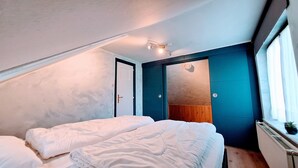 A bedroom with two beds, a ceiling light, a door, and a window. - WesterOurthe 6 persons with sauna (Durbuy)