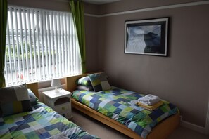 Ein Schlafzimmer mit zwei Einzelbetten, einem Nachttisch, einer Lampe und einem gerahmten Bild an der Wand.