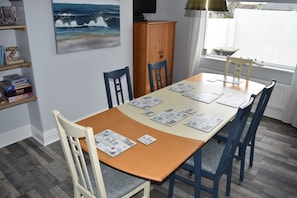 Ein Essbereich mit einem Holztisch, blauen Stühlen und einem Gemälde einer Strandansicht an der Wand.