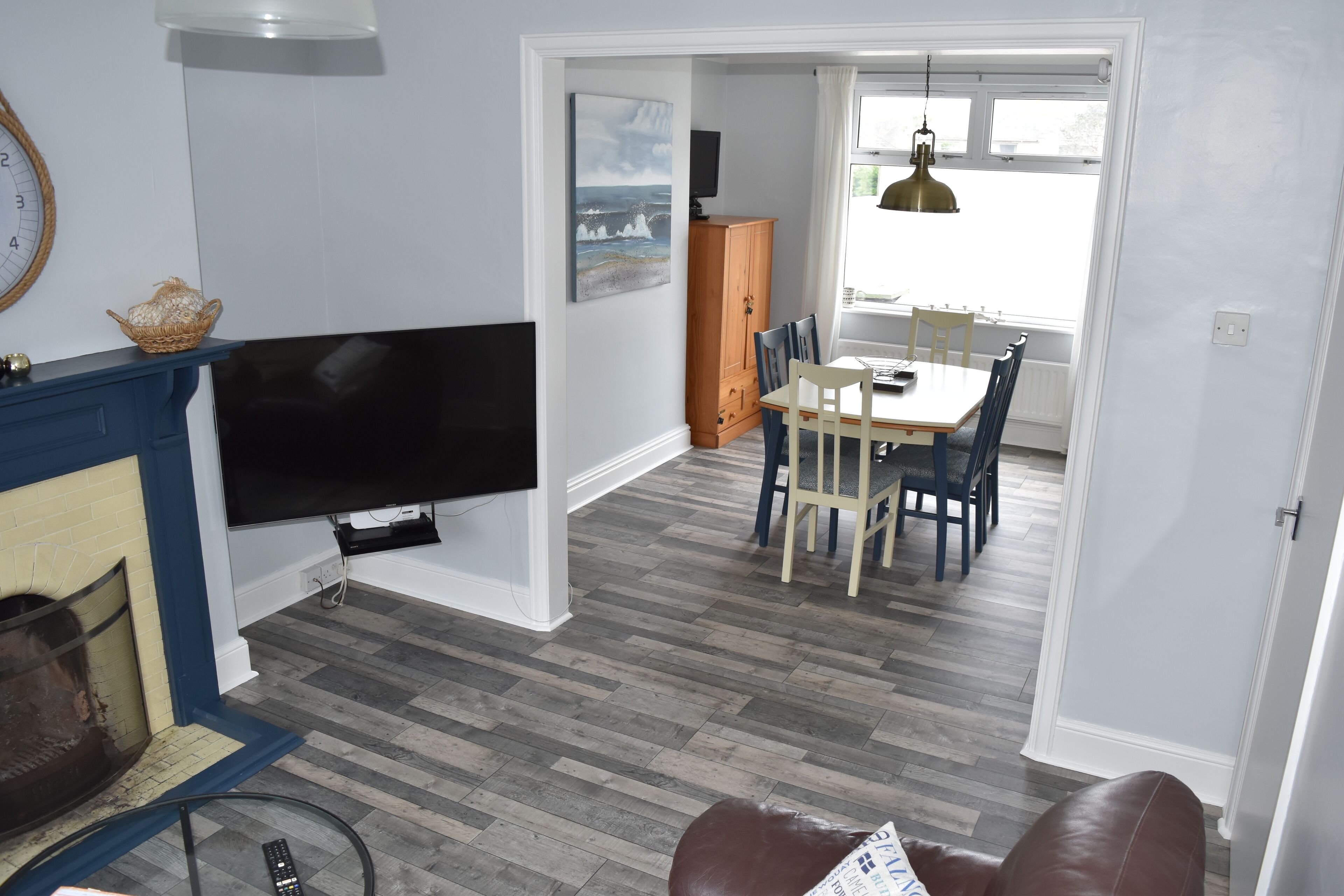 A living room with a TV, fireplace, dining area, and a view through a doorway.