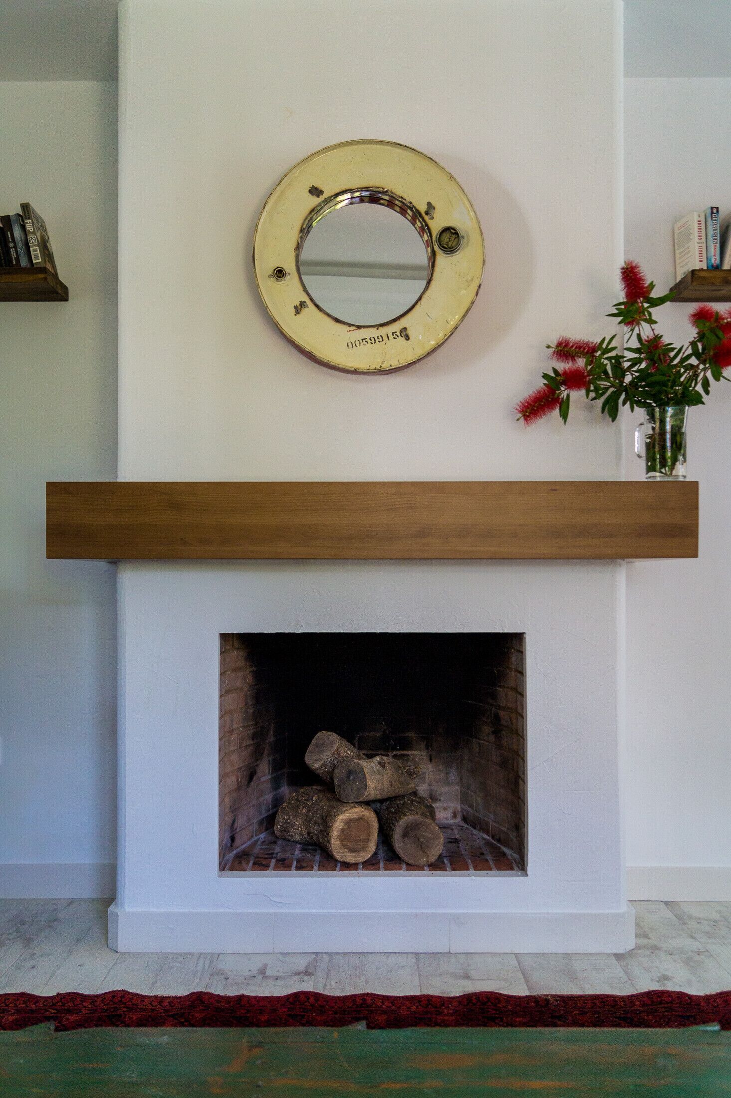 A fireplace with a wooden mantel and a mirror above it.