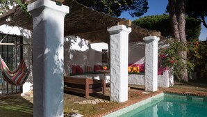 Un área de piscina con una pared blanca, una hamaca y un banco.