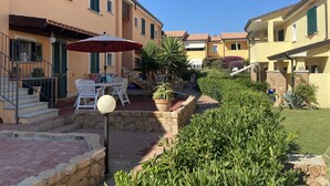 A courtyard with outdoor seating, stone steps, and potted plants. - directly on the sea new apartment with garden and swimming pool (badesi)
