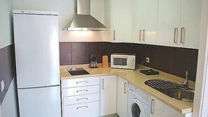 A compact kitchen with a refrigerator, microwave, sink, and a washing machine.