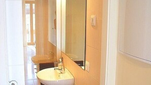 A narrow bathroom with a sink, mirror, and a towel hanging on the wall.