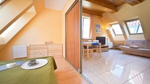 A cozy attic bedroom with a dining area, a sofa, and a TV. - Comfortable apartment in the heart of Gdansk Old Town (Gdansk)