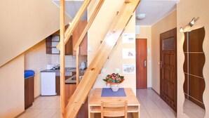 A compact kitchen with wooden beams, a dining table with chairs, and a small refrigerator. - Comfortable apartment in the heart of Gdansk Old Town (Gdansk)