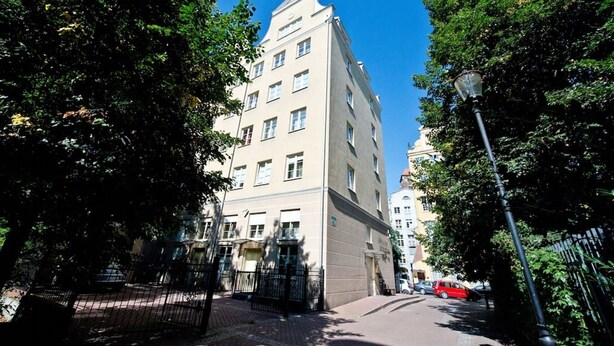 A multi-story building with a classic architectural style, surrounded by trees and a paved sidewalk. - Comfortable apartment in the heart of Gdansk Old Town (Gdansk)