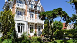 Una gran casa de estilo victoriano, ornamentada, con un balcón destacado y un jardín cuidado.