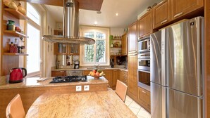 Una cocina moderna con armarios de madera, electrodomésticos de acero inoxidable y una isla central.