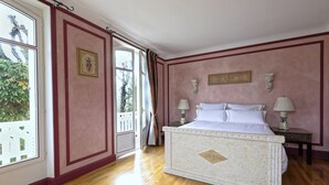 Un dormitorio con una cama grande, suelo de madera y vista a través de una puerta abierta.