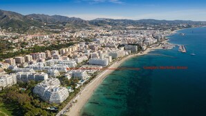 Eine Luftaufnahme einer Küstenstadt mit einem markanten Hotelkomplex namens Complex Marbella House.