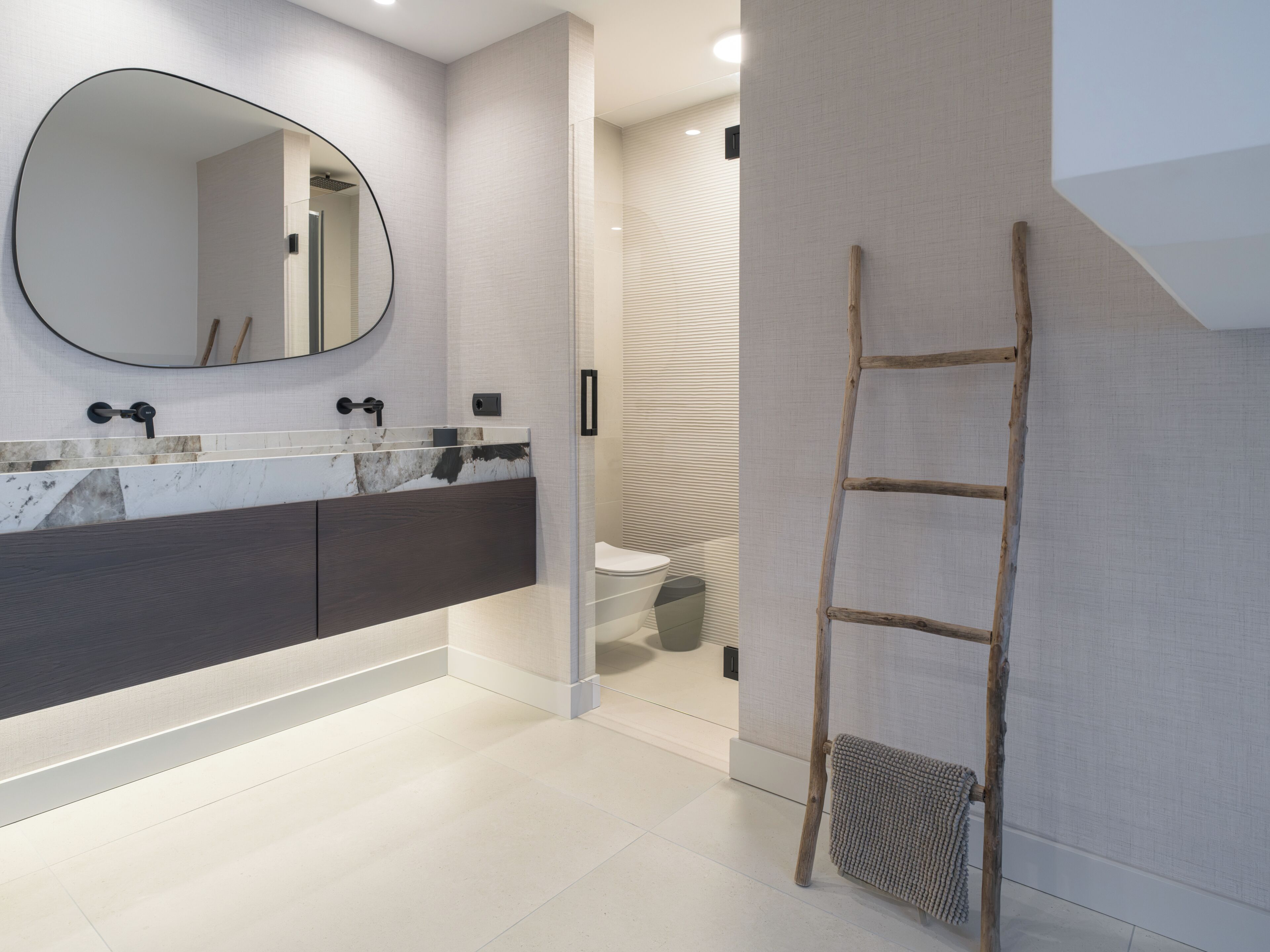 A modern bathroom with a large mirror, a wooden ladder, and a towel rack.