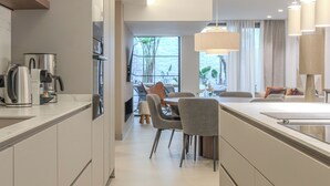 Eine moderne Küche mit integrierten Geräten, ein Essbereich mit Stühlen und ein großes Fenster.
