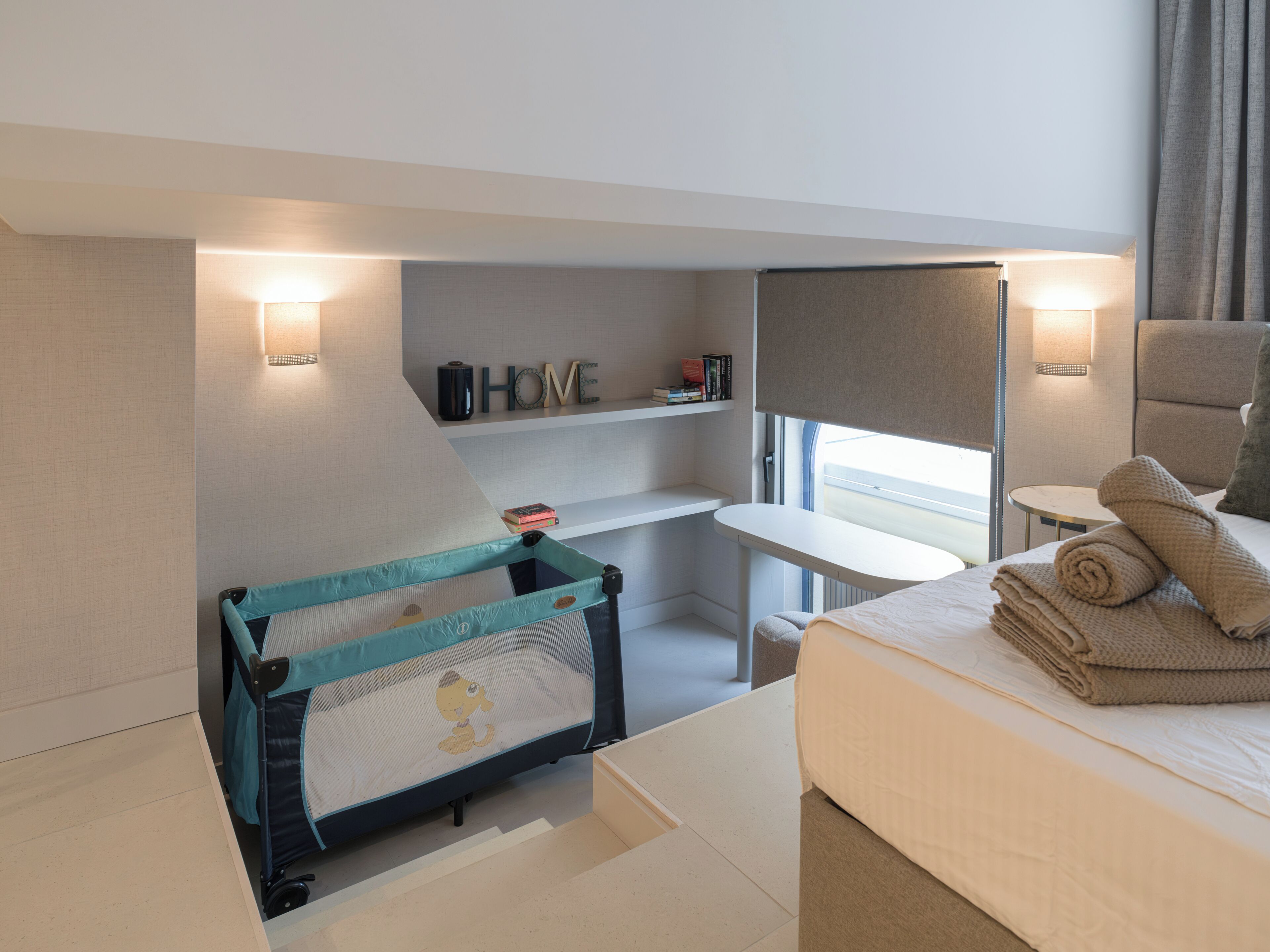 A modern hotel room with a convertible bed, a desk, and a small seating area.