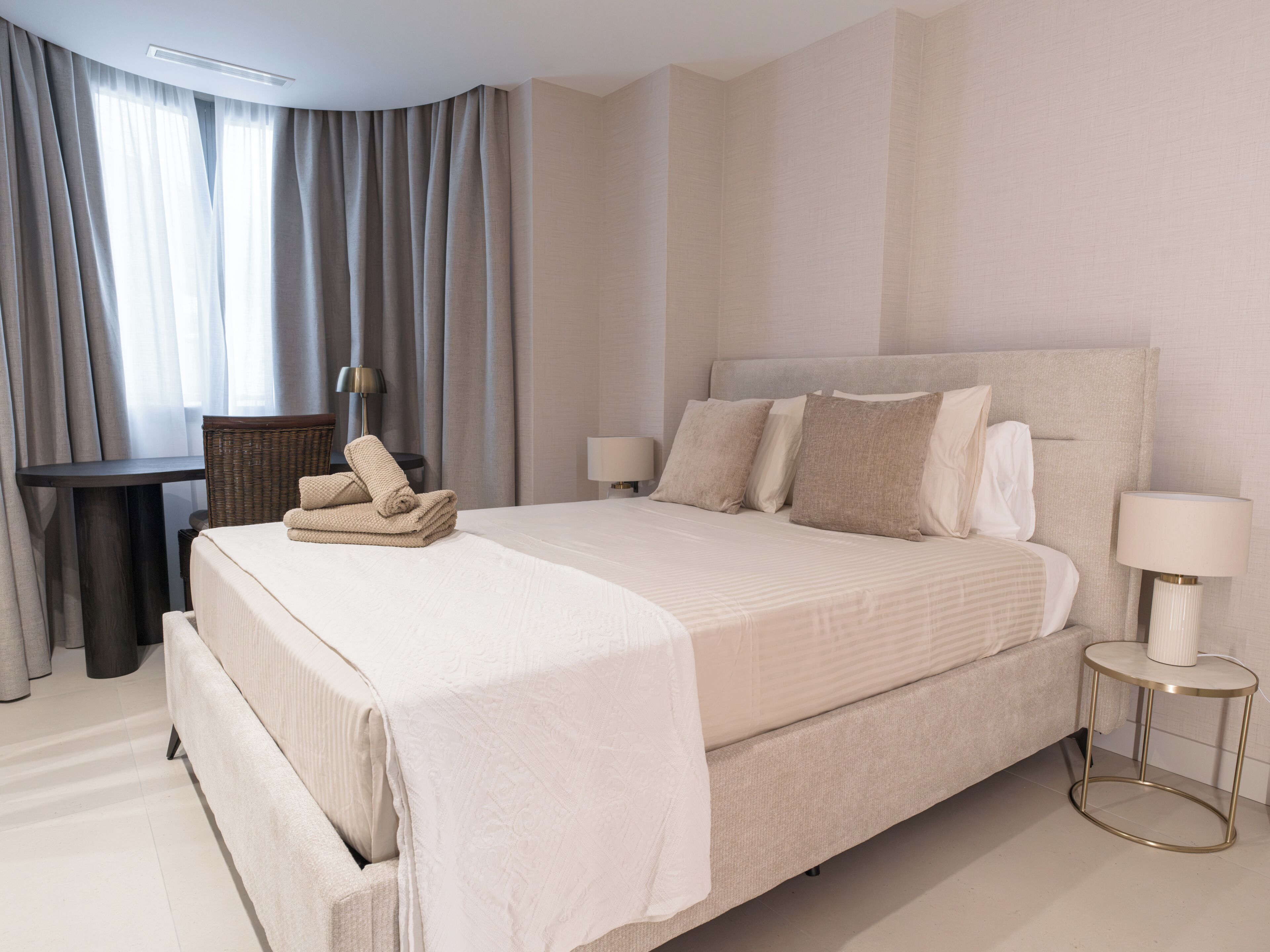 Een hotelkamer met een groot bed, een klein tafeltje, een stoel en een lamp.