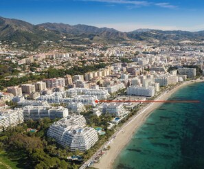 An aerial view of a coastal city with a prominent hotel complex named Complex Marbella House.