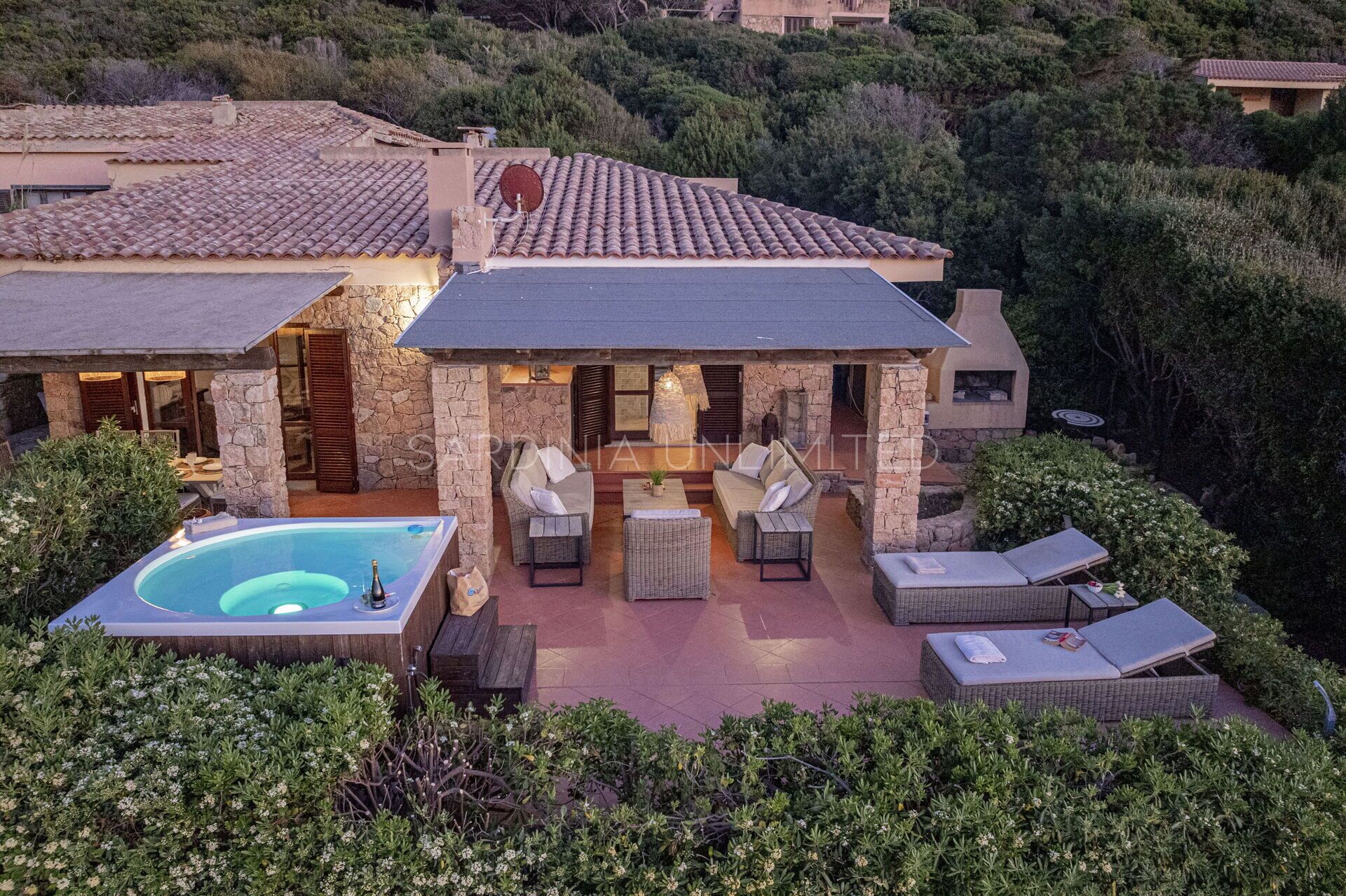 Une maison avec une piscine, un espace extérieur aménagé et une façade en pierre.