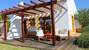 A covered outdoor seating area with wooden furniture and a pergola structure.