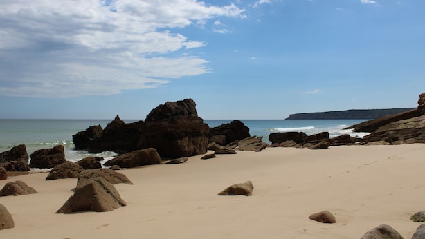 A beach with large rocks and a clear sky.