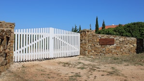 A gated entrance with a stone wall and a white picket fence.