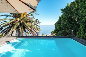 A swimming pool with a view of the sea and palm trees.
