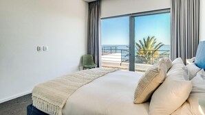 Ein Hotelzimmer mit einem großen Bett, Meerblick und einem Balkon.