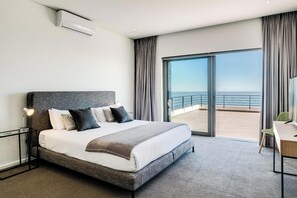 A modern hotel room with a large bed, a desk, and a view of the sea. - Incredible Luxury Villa w Ocean Vistas The Views (Cape Town)