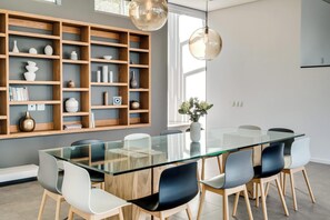 Un comedor moderno con una mesa de vidrio, sillas de madera y una estantería empotrada.