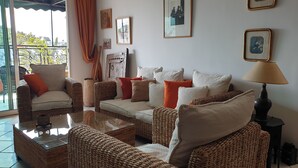Una sala de estar con muebles de mimbre, una mesa de centro de vidrio y una lámpara.