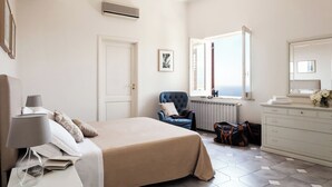 Un dormitorio con cama, una silla, cómoda y ventana con vistas.