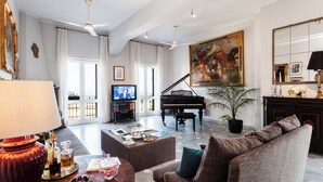 Un amplio salón con un piano de cola, un televisor y un cuadro grande.