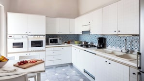 Una cocina moderna con gabinetes blancos, microondas, estufa y cafetera.