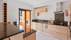 Una cocina moderna con encimera de granito, armarios de madera y campana extractora de acero inoxidable.