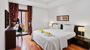 Habitación de hotel con una cama grande, dos mesitas de noche con lámparas, una silla y vistas al exterior.