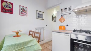 Eine kompakte Küche mit Esstisch, Stühlen, Heizkörper, Gaskochfeld und kleinem Backofen.
