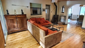 A cozy living room with a wooden sofa, a wooden cabinet, and a fireplace. - Sarlat La Caneda: SPACIOUS APARTMENT WITH GARDEN AND PRIVATE SWIMMING POOL (Sarlat-la-Canéda)
