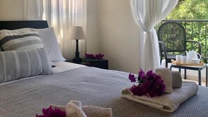Hotellihuone, jossa on suuri sänky, yöpöytä lampun kanssa ja näkymä ulos.