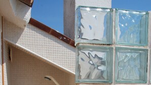 En duschhörna med en kaklad vägg och en avskärmning av glasblock.