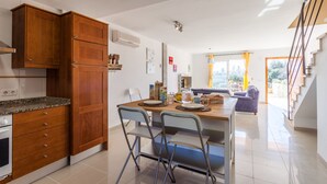 Una cocina moderna con armarios de madera, encimera de granito y un comedor con mesa y sillas.