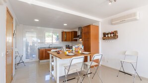 Una cocina moderna con una isla de madera, sillas blancas y una mesa de comedor.