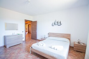 Um quarto com uma cama de madeira, uma mesinha de cabeceira, um criado-mudo, um penteado e um espelho.