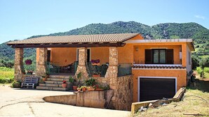 A single-story house with a tiled roof, stone pillars, and a covered porch with potted plants. - Sa Ingia by All4sardinia (Cardedu)