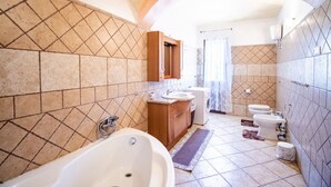 A bathroom with a freestanding bathtub, a wooden vanity, a washing machine, and two toilets. - Sa Ingia by All4sardinia (Cardedu)