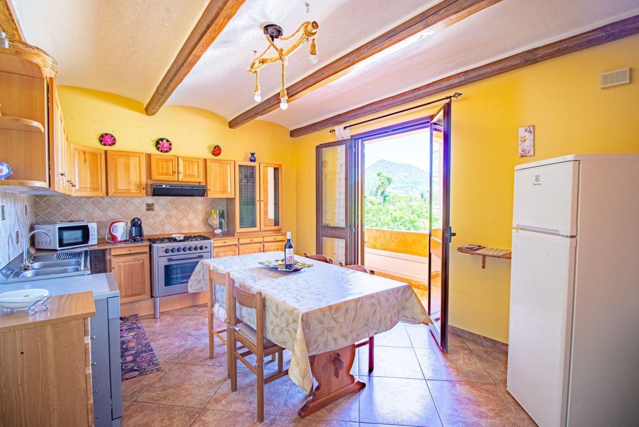 Una cocina con armarios de madera, estufa, microondas y una mesa de comedor con sillas.