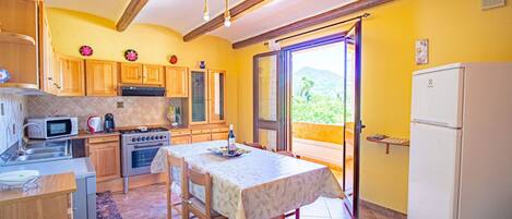 Una cocina con armarios de madera, estufa, microondas y una mesa de comedor con sillas.