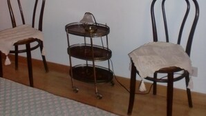 Une pièce avec deux chaises en bois, une petite table et un miroir fixé au mur.