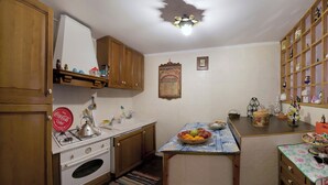 Une cuisine avec des meubles de rangement en bois, une cuisinière à gaz, un évier et un panier de fruits posé sur le comptoir.